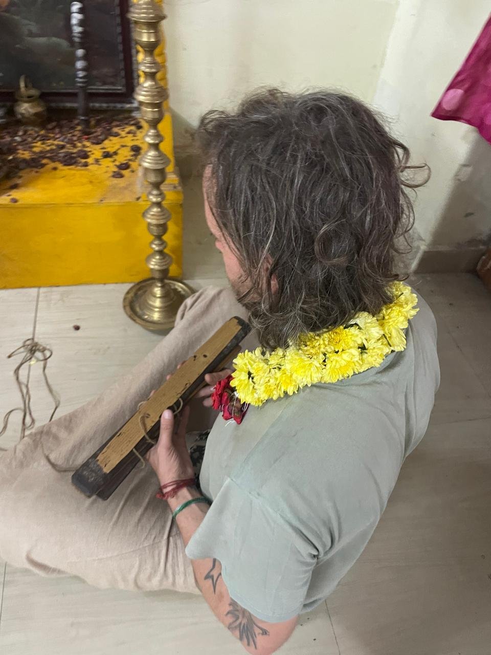 A seeker holding a palm-leaf manuscript during a consultation