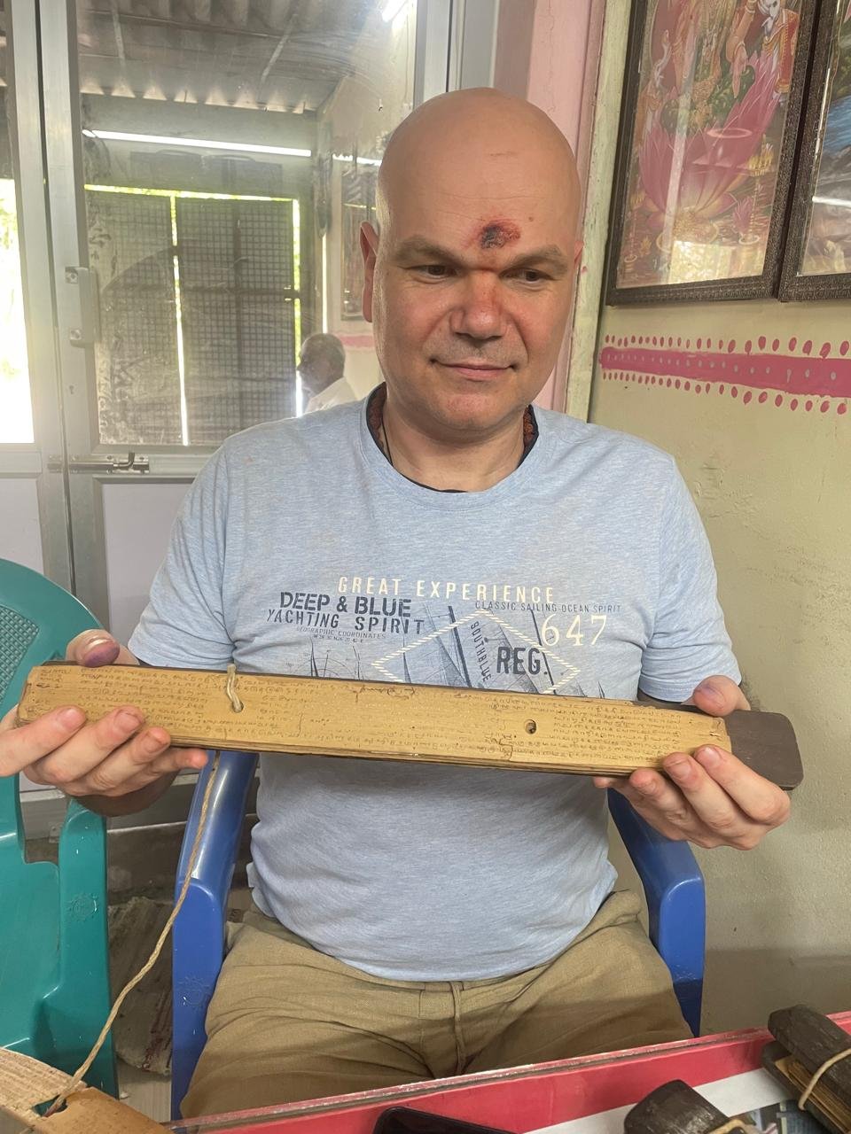 A seeker examining an inscribed olai chuvadi palm leaf