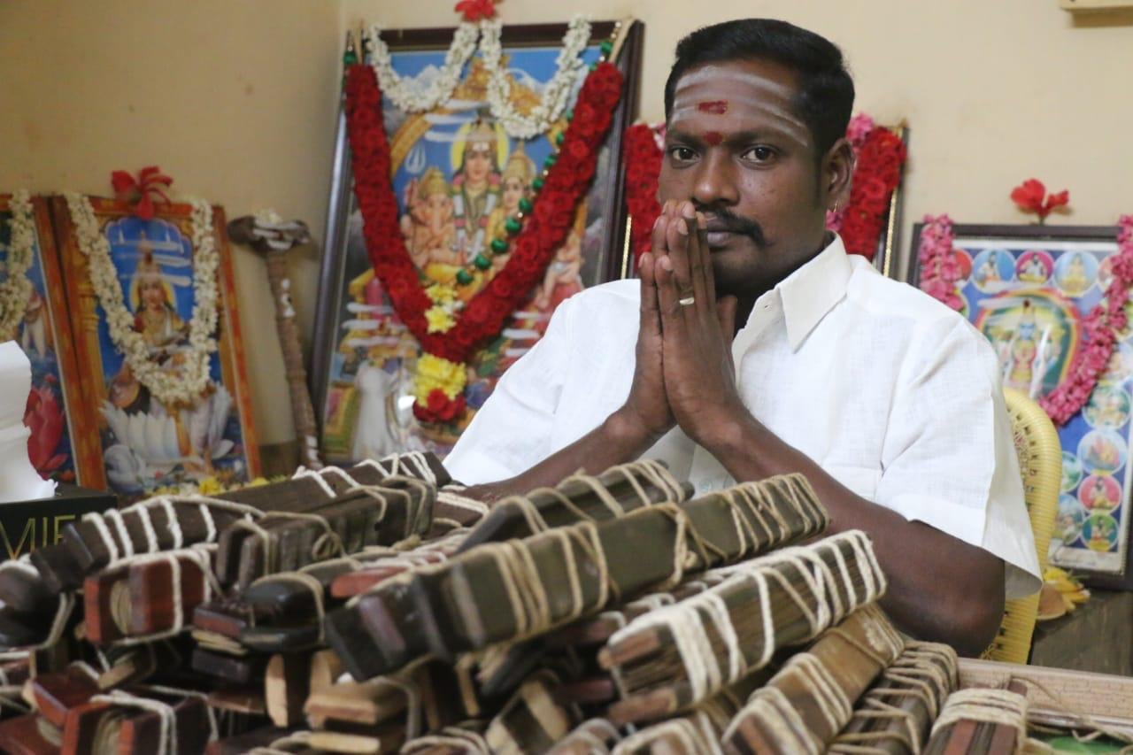 Guruji B.S. Vignesh Swamy in prayer before palm-leaf manuscript bundles